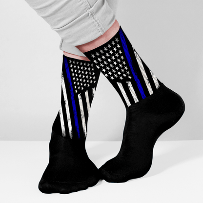 Black socks with American flag design featuring a blue stripe, worn by a person on a light gray background.