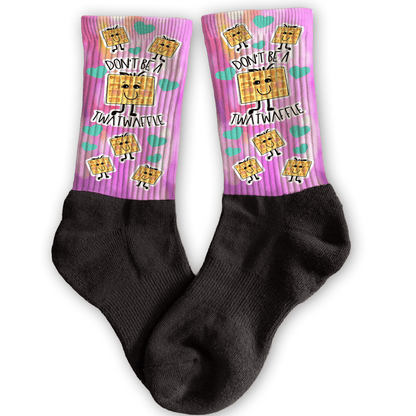 Funny crew socks with “Don’t Be a Twatwaffle” waffle design, pink background, unique rude adult stocking stuffer.