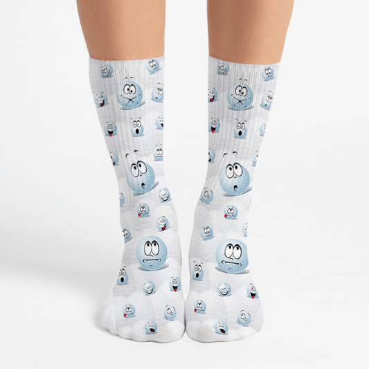 White crew socks with cartoon golf ball faces. Funny men’s gift for golfers or novelty sports sock lovers.
